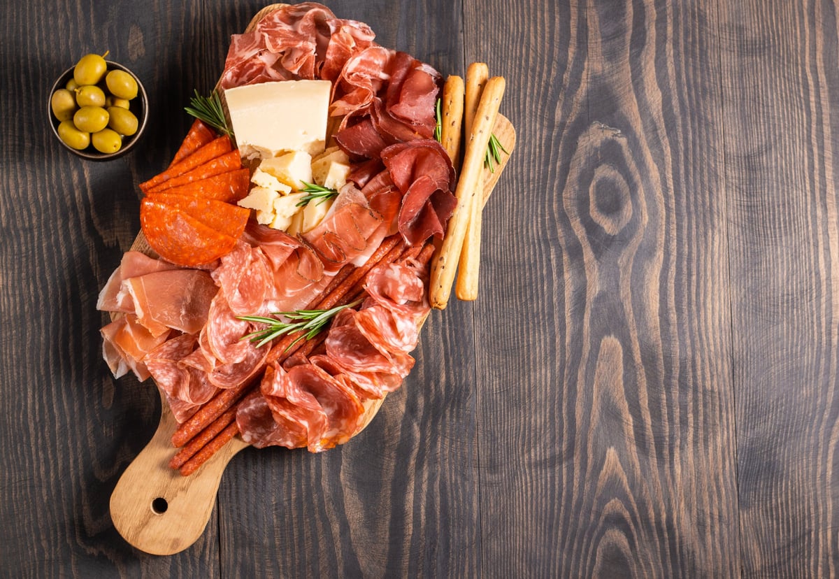Close view of prosciutto, salami and olives on a charcuterie board