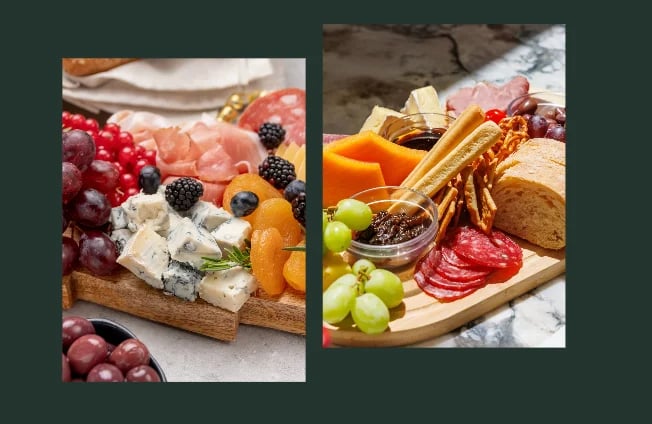 Two charcuterie boards displaying cured meats, cheeses, fresh berries, grapes, bread, and olives on wooden serving platters